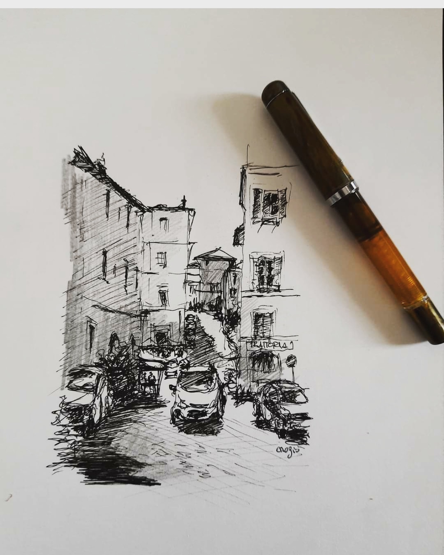 Disegno a penna di una strada romana accanto alla penna dell’artista